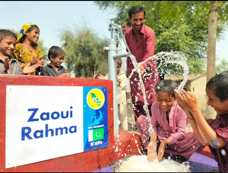 Enfants riant autour d'une pompe à eau active.