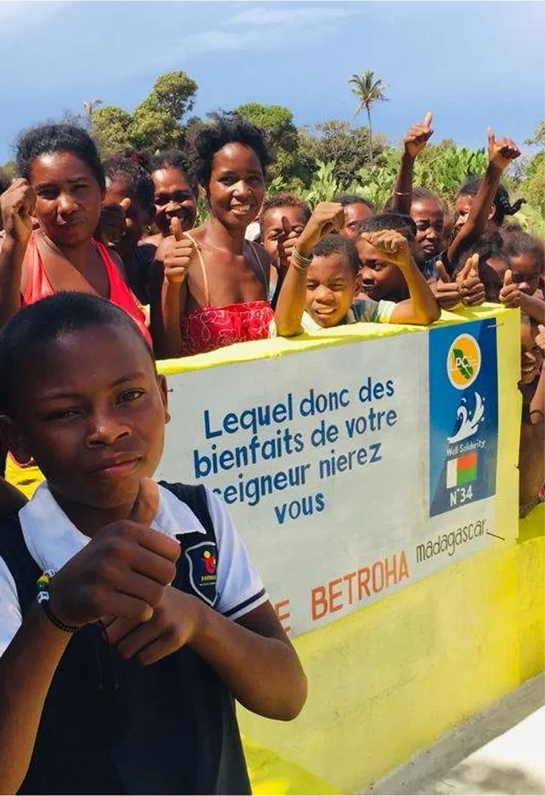 Groupe de personnes souriant devant un panneau.