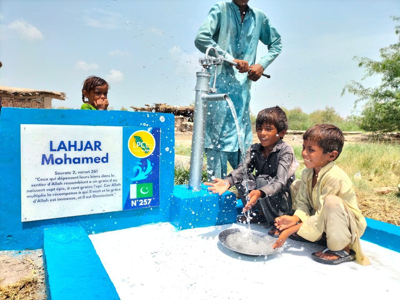 Enfants jouent avec l'eau d'une pompe.