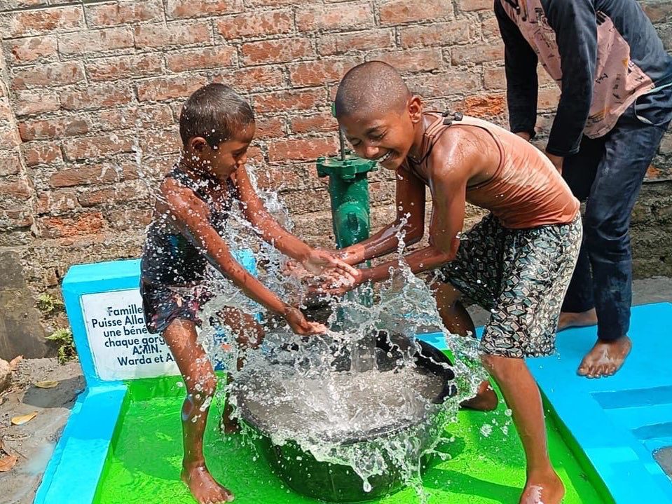 Enfants jouent avec de l'eau d'une pompe.