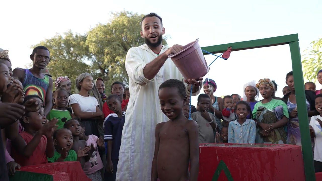 Groupe d'enfants autour d'un puits avec un adulte.