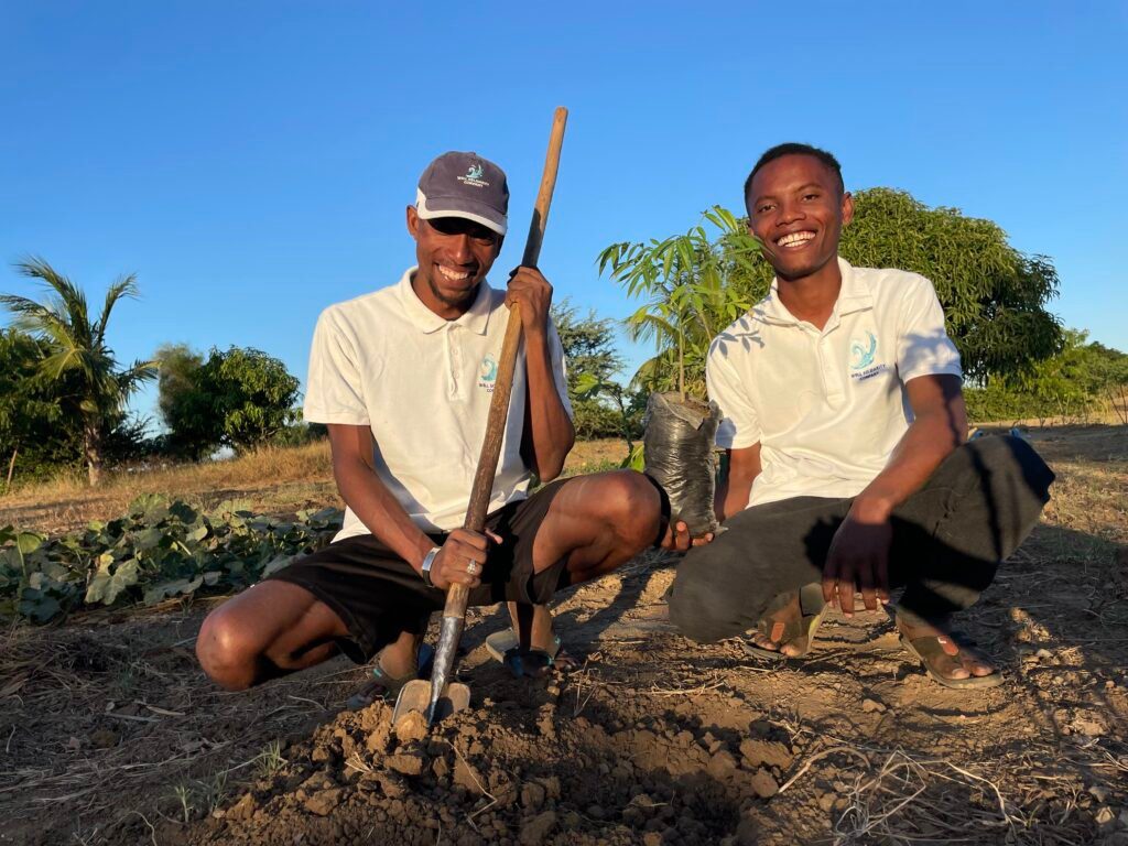 Deux personnes souriantes plantent un arbre.