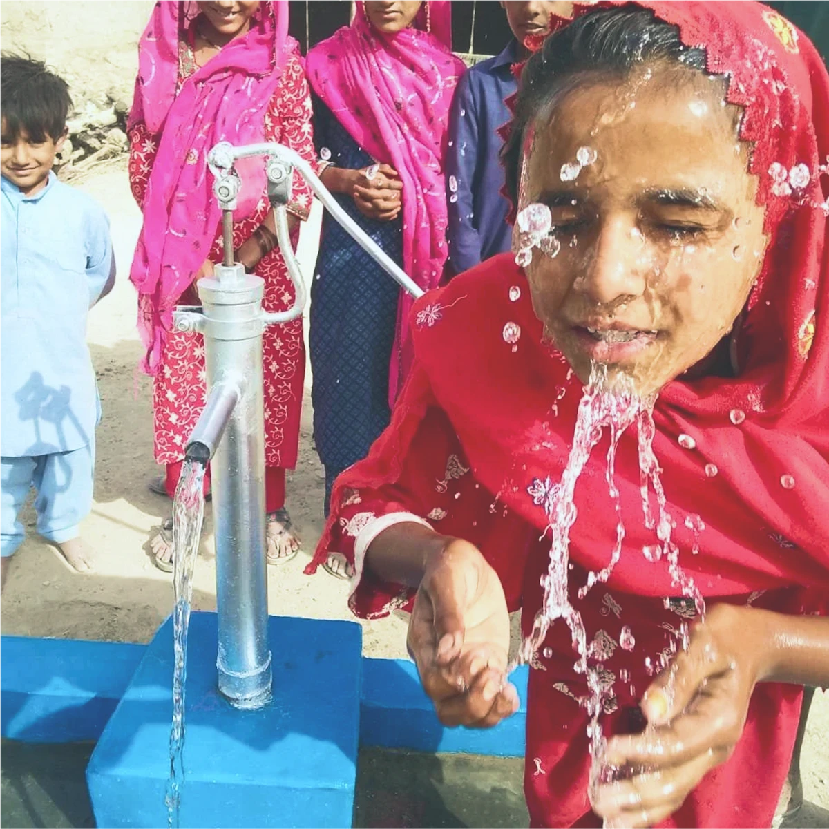 Femme puisant de l'eau à une pompe manuelle.